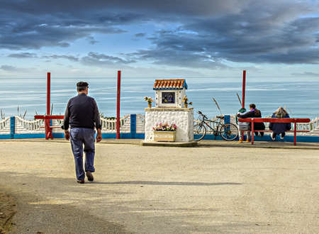 Landscape with an adult man walking towards the edge of the coastの写真素材