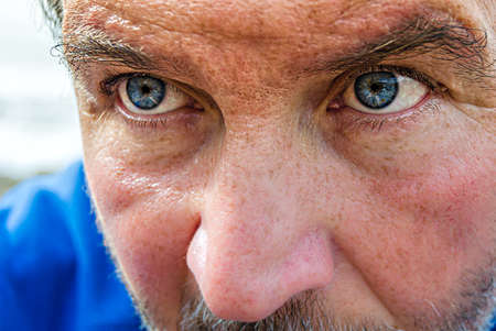 Portrait of a man with blue eyes and a blue blouse by the seaの写真素材