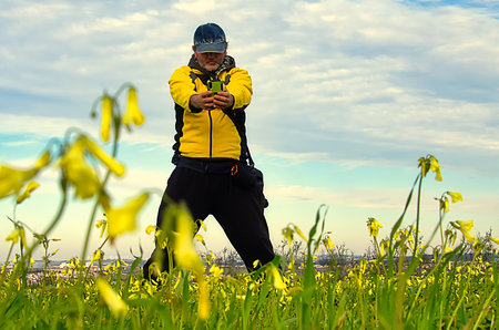 Man in yellow with arms outstretched on a field of yellow flowers