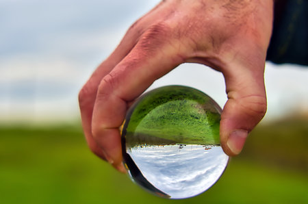 Glass globe in the hand of a man with a rural landscape background