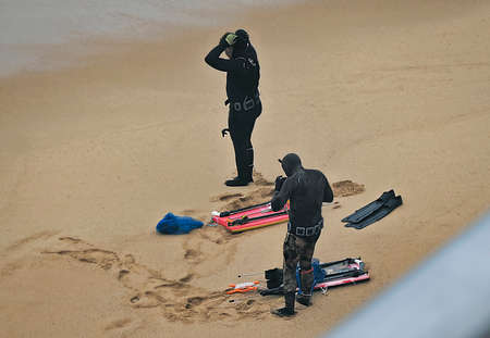 Two divers preparing to dive on a beach in the cityの写真素材