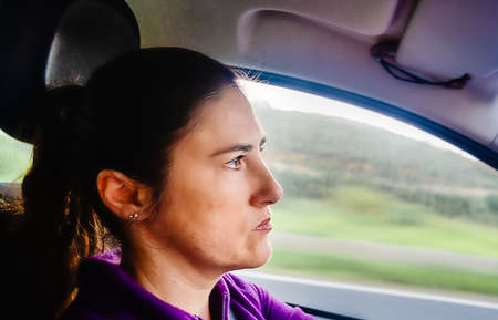 Profile of a concentrated woman behind the wheel driving a car