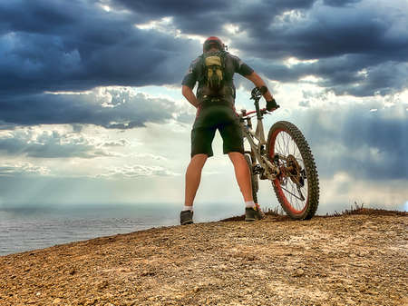 A cyclist in black gear on top of a hill near the oceanの写真素材