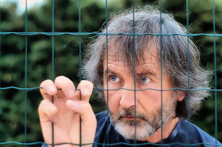 Blue-eyed man near a wire fence on a green backgroundの写真素材