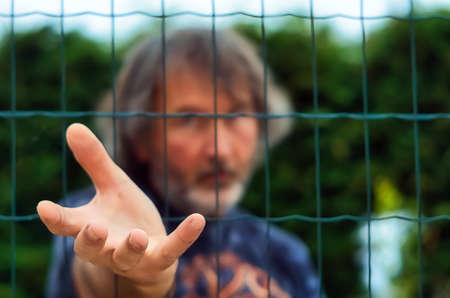 Blue-eyed man near a wire fence on a green backgroundの写真素材