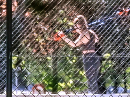 The young woman training in the park near a wire fence