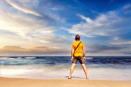 Adult male by the ocean looking out to sea at the water's edge
