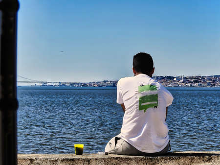 The person sitting by the river looking into the distance