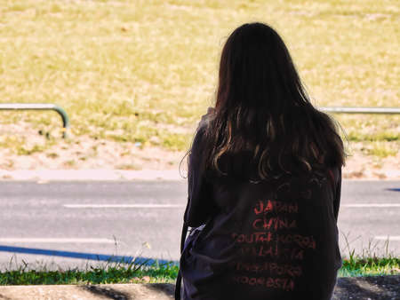 The young woman sitting on a bench consulting her mobile phone