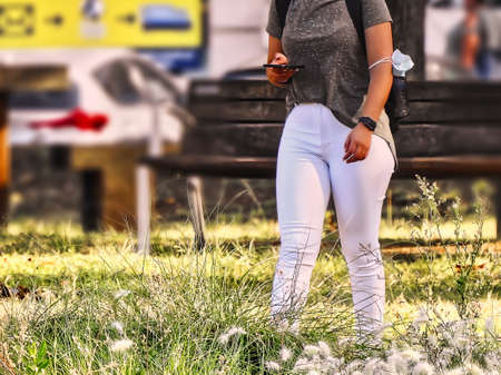 The young woman in white pants consulting her mobile phoneの写真素材