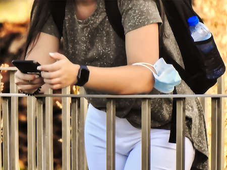 The young woman in white pants consulting her mobile phone