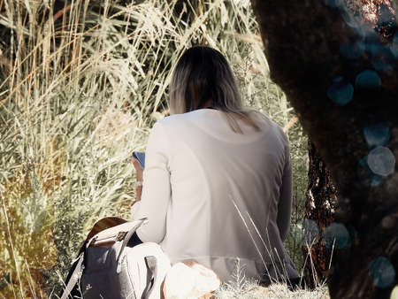 Woman in white blouse in the park near a treeの写真素材