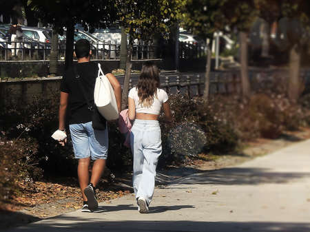 Couple of young people walking on an alley in the park