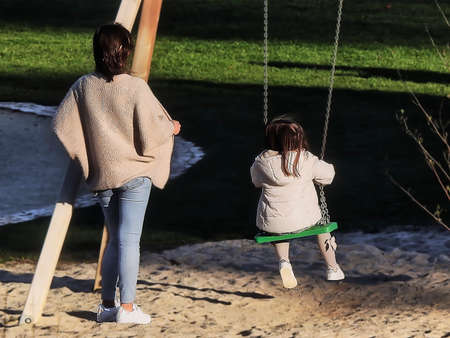 A little girl in a white jacket playing in the parkの写真素材
