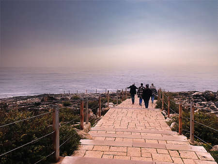A group of tourists on a wooden walkway by the oceanの写真素材