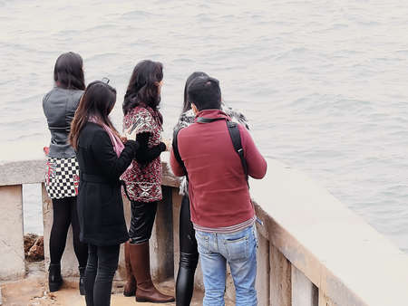 People on the seafront looking at the ocean on a winter day
