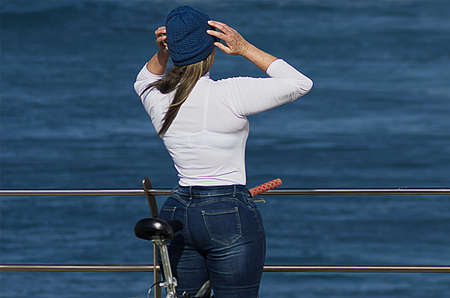 Woman in blue cap by the ocean on a bicycleの写真素材
