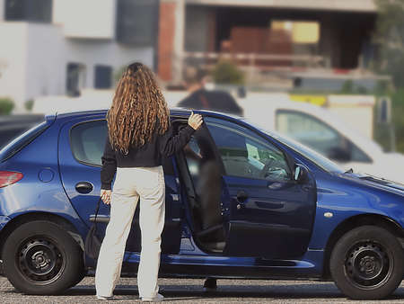 Curly-haired young woman waiting in a parking lotの写真素材