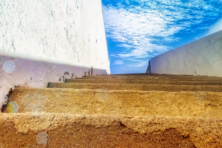 View from an alley on the stairs to a blue skyの写真素材