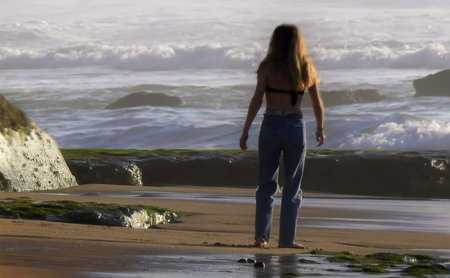 Teenager in jeans and bra by the oceanの写真素材