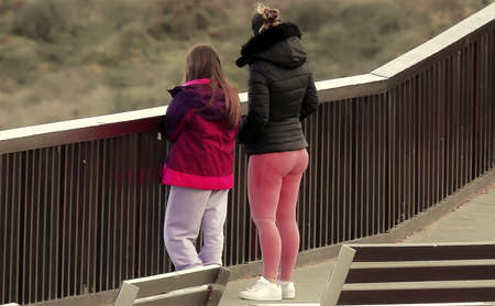 A woman in pink tights with a girl near a wooden fenceの写真素材