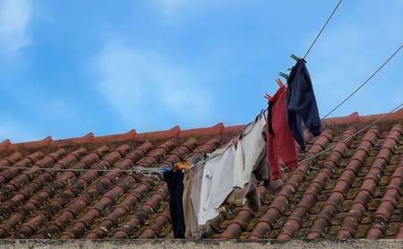 Dry laundry on the tile roof of a houseの写真素材