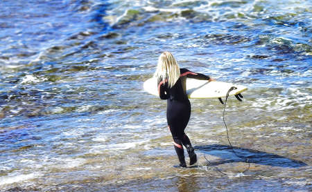 Blonde surfer in black warming up by the ocean