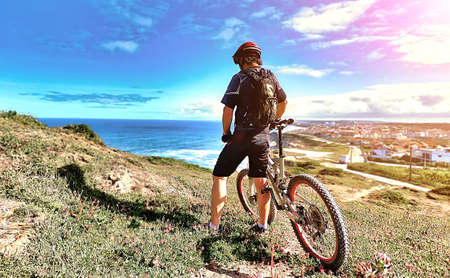 Cyclist looking at the ocean from a hill near the city