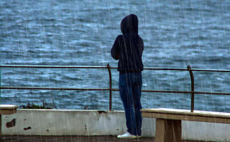 Woman admiring the ocean on the seafront on a rainy day