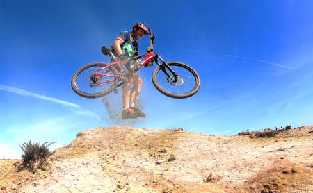 Cyclist with red helmet and blue gear pedaling near the ocean