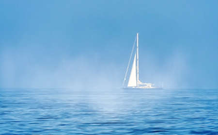 Minimalist view with a sailing boat floating in the fogの写真素材