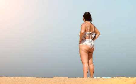 Woman in bikini on the beach sand on a summer day