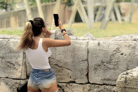 Woman in shorts taking photos with mobile phoneの写真素材