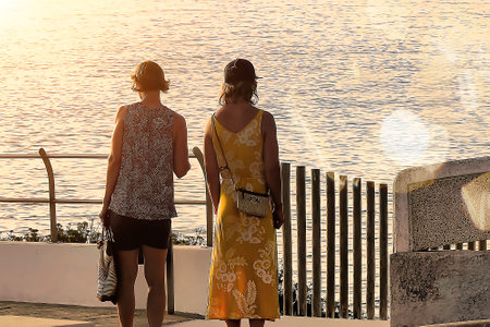 Two women looking out over the ocean at sunset