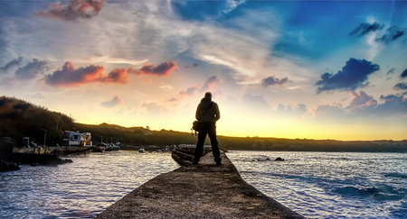 Seascape at sunset from a rocky beach and sky with a few cloudsの写真素材