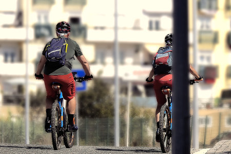 A pair of cyclists pedaling towards the cityの写真素材