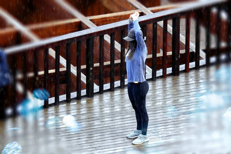Woman with a cap training in the rain by the oceanの写真素材