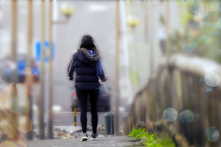 Woman in a cap walking through the rain on the sidewalk