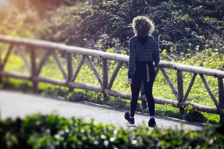 Woman in tracksuit walking next to a wooden railingの写真素材