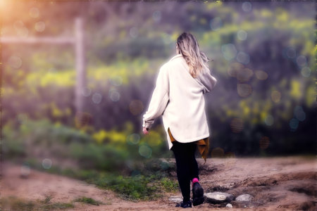 The blonde with a knitted jacket walking on a pathの写真素材