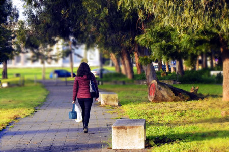Woman walking on the sidewalk in a parkの写真素材