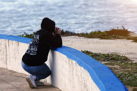 A photographer with a hood on his head photographing in the seaの写真素材