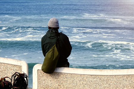 A lone man looking at the ocean from a pier