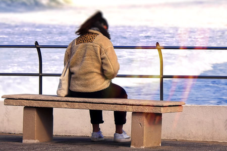 A young woman on a bench by the oceanの写真素材