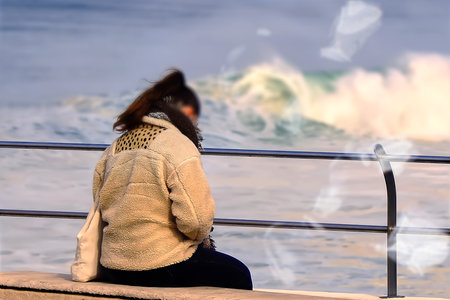 A young woman on a bench by the oceanの写真素材