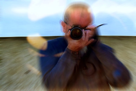 Adult man with a camera taking a picture in a shop windowの写真素材