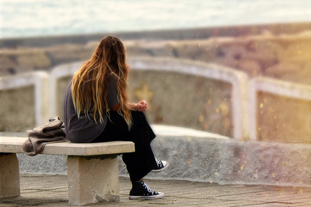 The blonde in black pants talking on the phone on the cliffの写真素材