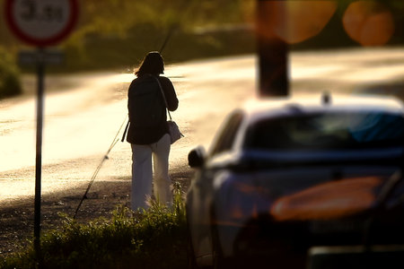 Woman walking among cars with the sun in front of herの写真素材