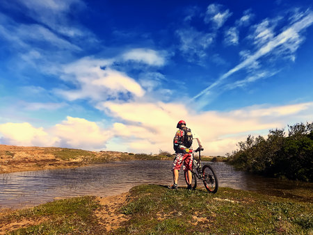 Cyclist with a red helmet pedaling by the oceanの写真素材