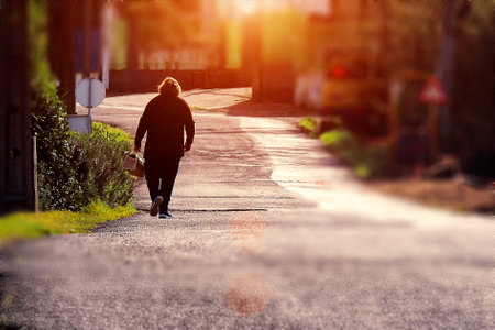 A woman walking with the sun in front of herの写真素材